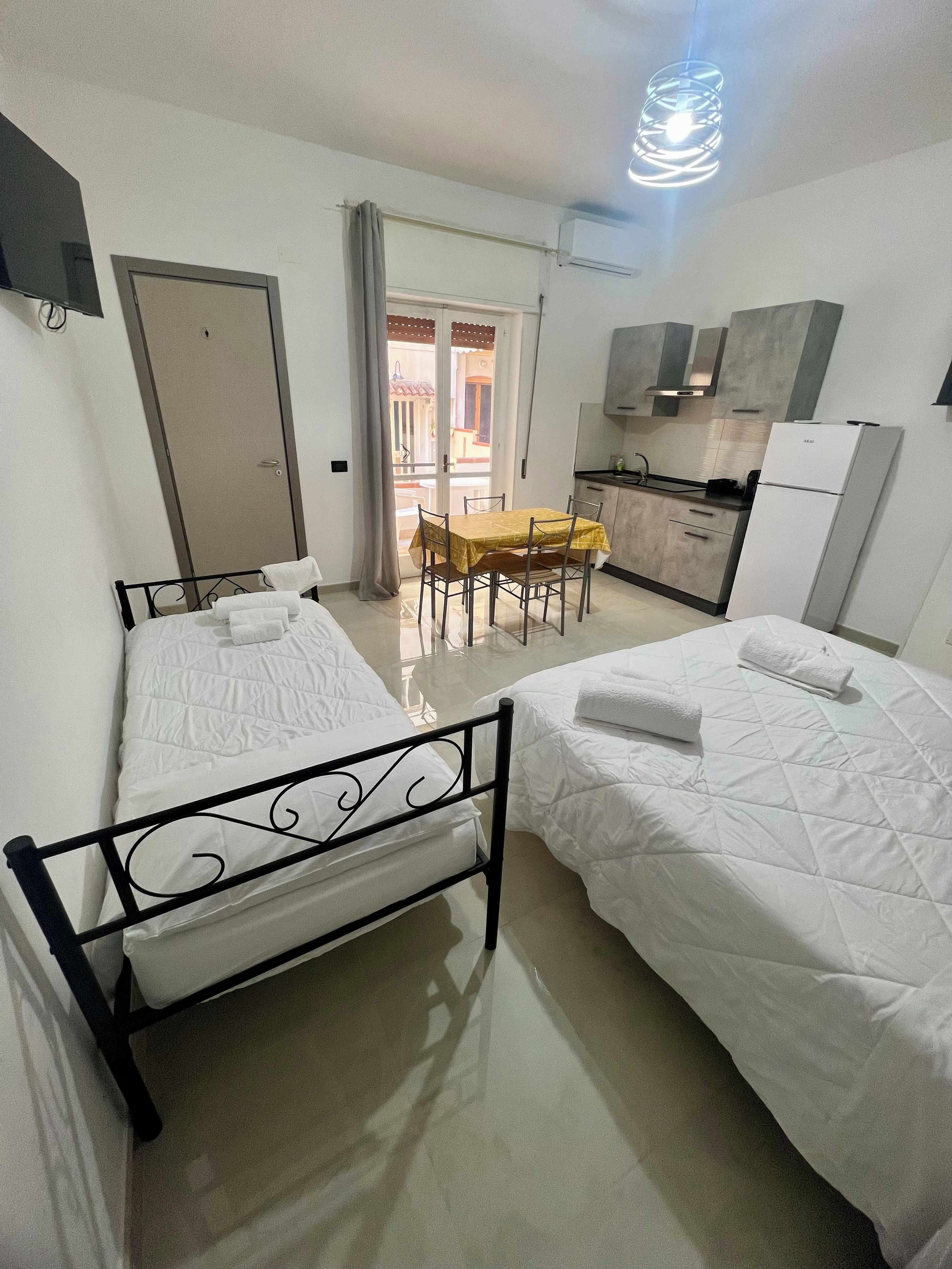 A hotel room with two beds, a dining table, and a kitchenette.