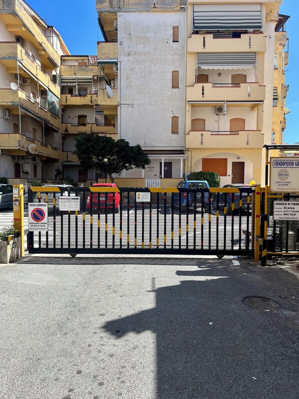 Una entrada protegida por un portón a un edificio residencial con varios balcones y un letrero que indica propiedad privada.