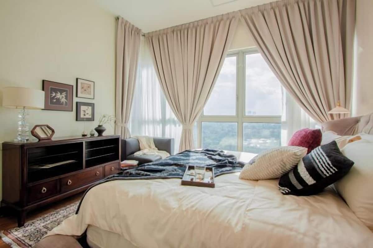 Ein Schlafzimmer mit Bett, Schminktisch, Fenster mit Vorhängen und Wandbildern.