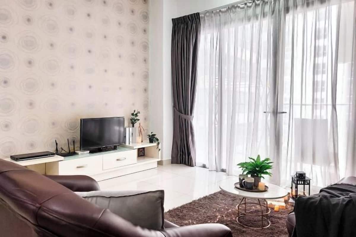 Ein modernes Wohnzimmer mit Flachbildfernseher, einer Couch, einem Couchtisch und einem Fenster mit transparenten Vorhängen.