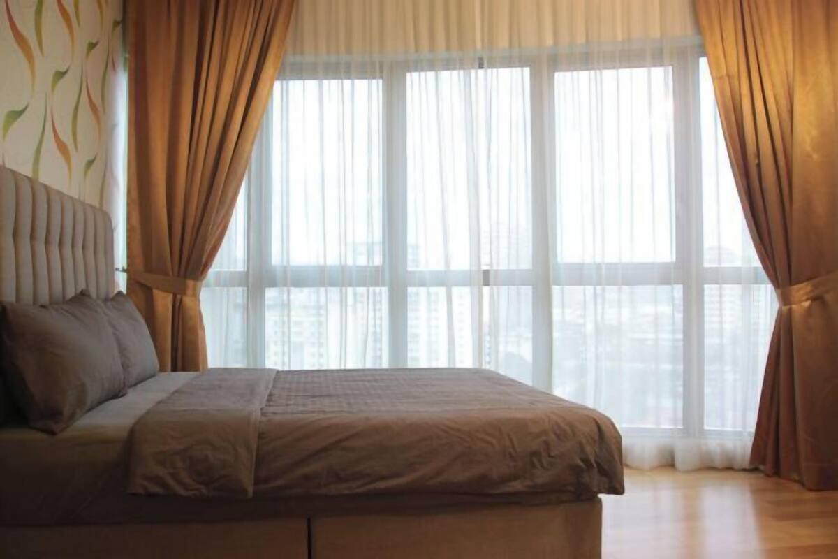 Ein Schlafzimmer mit einem Bett, Vorhängen und einem großen Fenster.