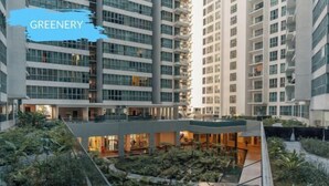 Un edificio moderno de gran altura con varios balcones y un patio central con vegetación.