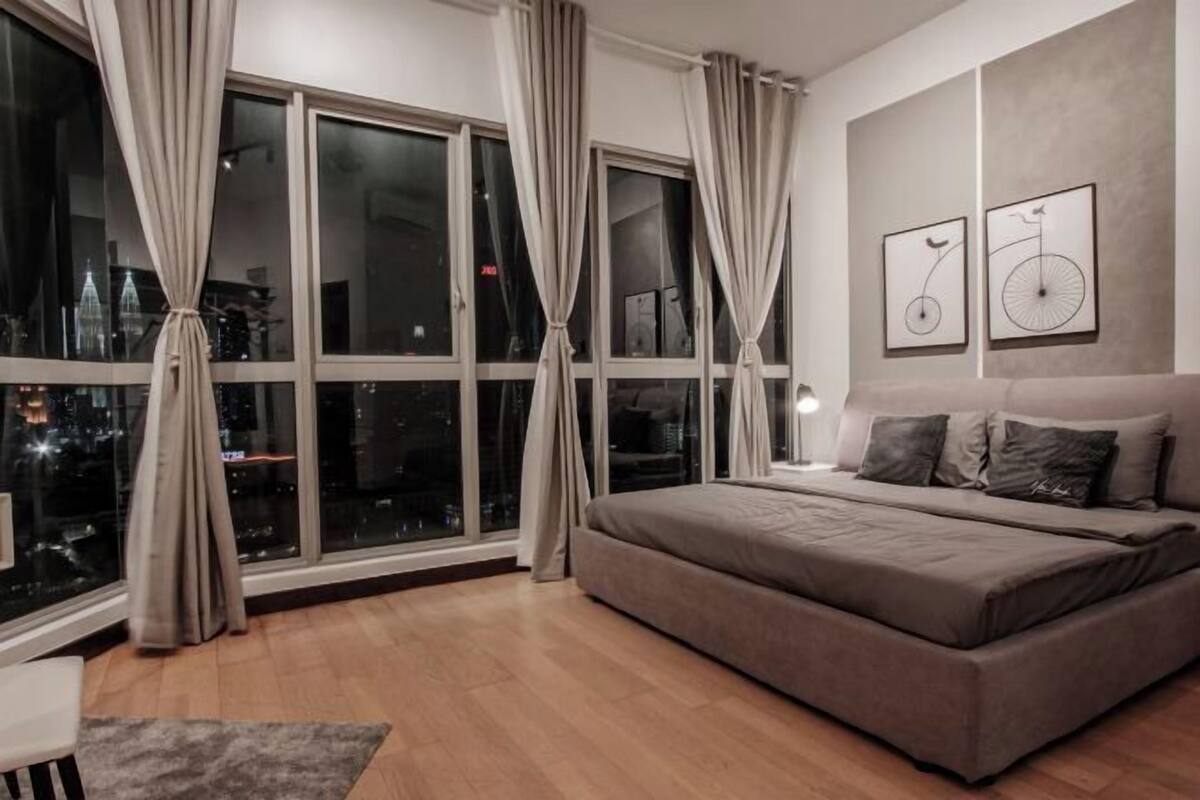Ein modernes Schlafzimmer mit großem Fenster, einem Bett und zwei an der Wand befestigten Kunstwerken.