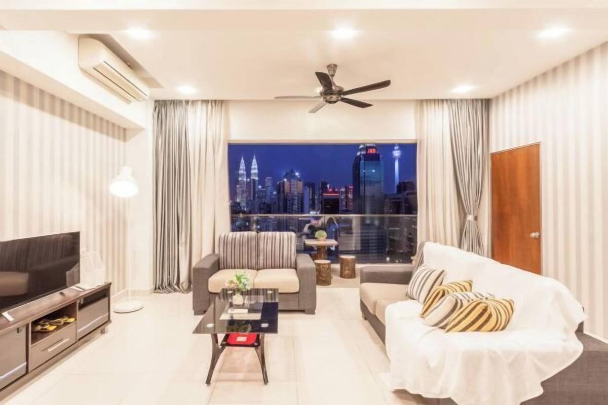 Ein modernes Wohnzimmer mit Fernseher, Sofa und Couchtisch, mit Blick auf die Stadt durch große Fenster.