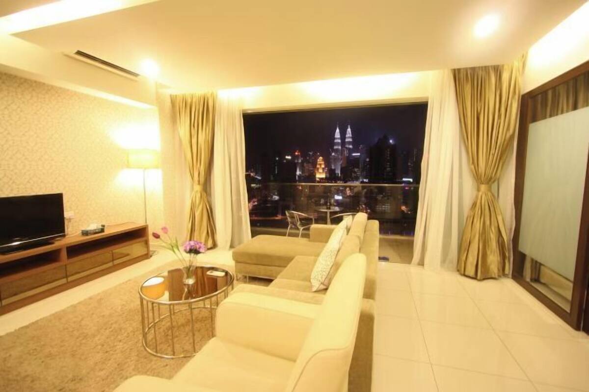 Ein modernes Wohnzimmer mit einer Couch, einem Fernseher und Blick auf eine nächtliche Skyline.