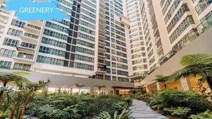 Un edificio moderno de gran altura con un patio central repleto de vegetación y un sendero pavimentado.