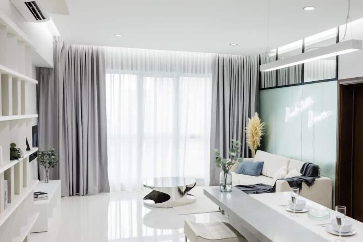 Ein modernes Wohnzimmer mit einem weißen Sofa, einem runden Couchtisch und einem Essbereich mit einem weißen Tisch, der gedeckt ist.