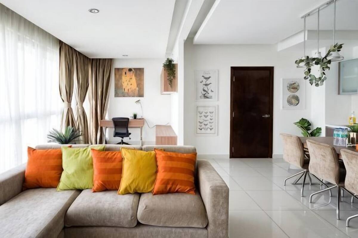 Ein modernes Wohnzimmer mit einer Couch, einem Esstisch, Stühlen, einem Schreibtisch mit Stuhl und Kunstwerken an den Wänden.