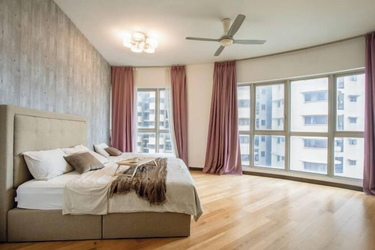 Ein Schlafzimmer mit einem Bett, einem Deckenventilator und großen Fenstern.