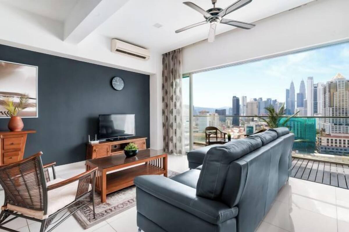 Ein modernes Wohnzimmer mit Sofa, Fernseher und Essbereich, mit Blick auf die Stadtlandschaft.