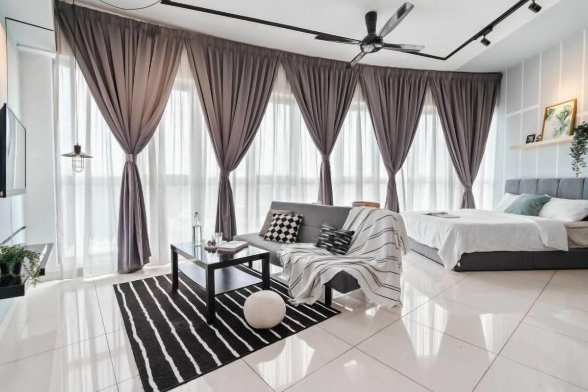 Ein modernes Wohnzimmer mit Sofa, Couchtisch, Bett und Deckenventilator.