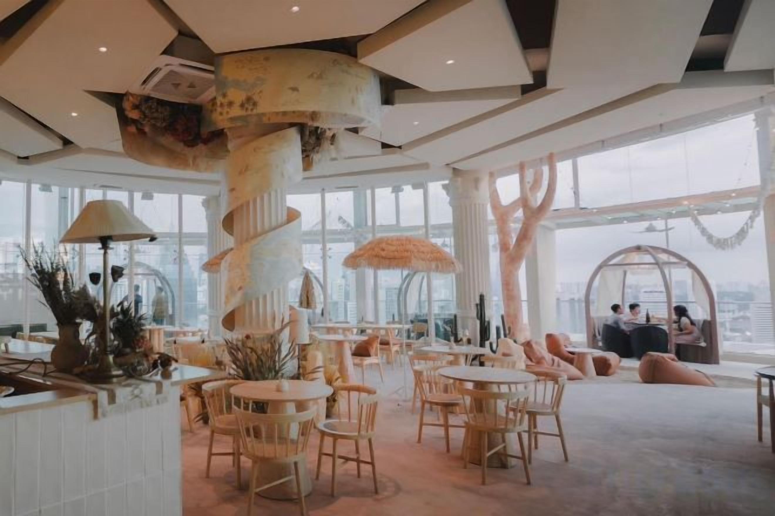 A spacious indoor area with round tables and chairs, large windows, and a unique spiral column structure.