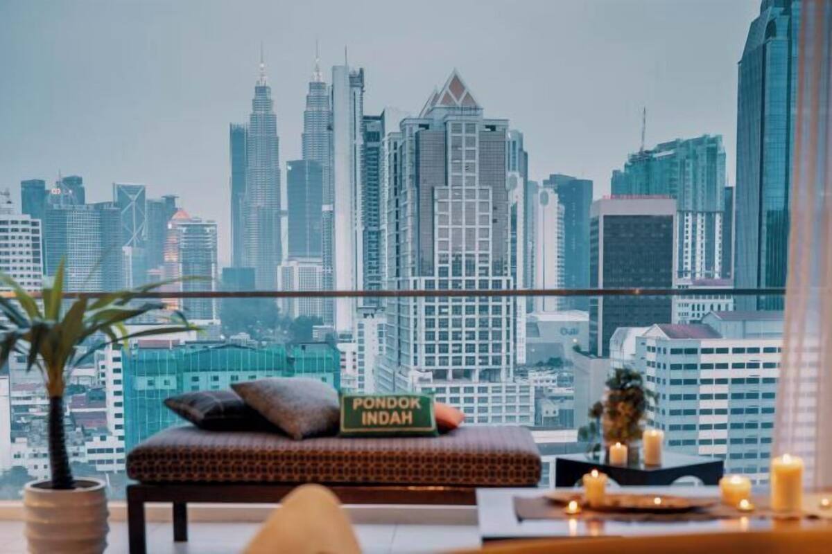 Ein Balkon mit Blick auf die Stadt, eine Sitzecke mit einem Schild, auf dem 'PONDOK INDAH' steht, und ein Blumentopf.