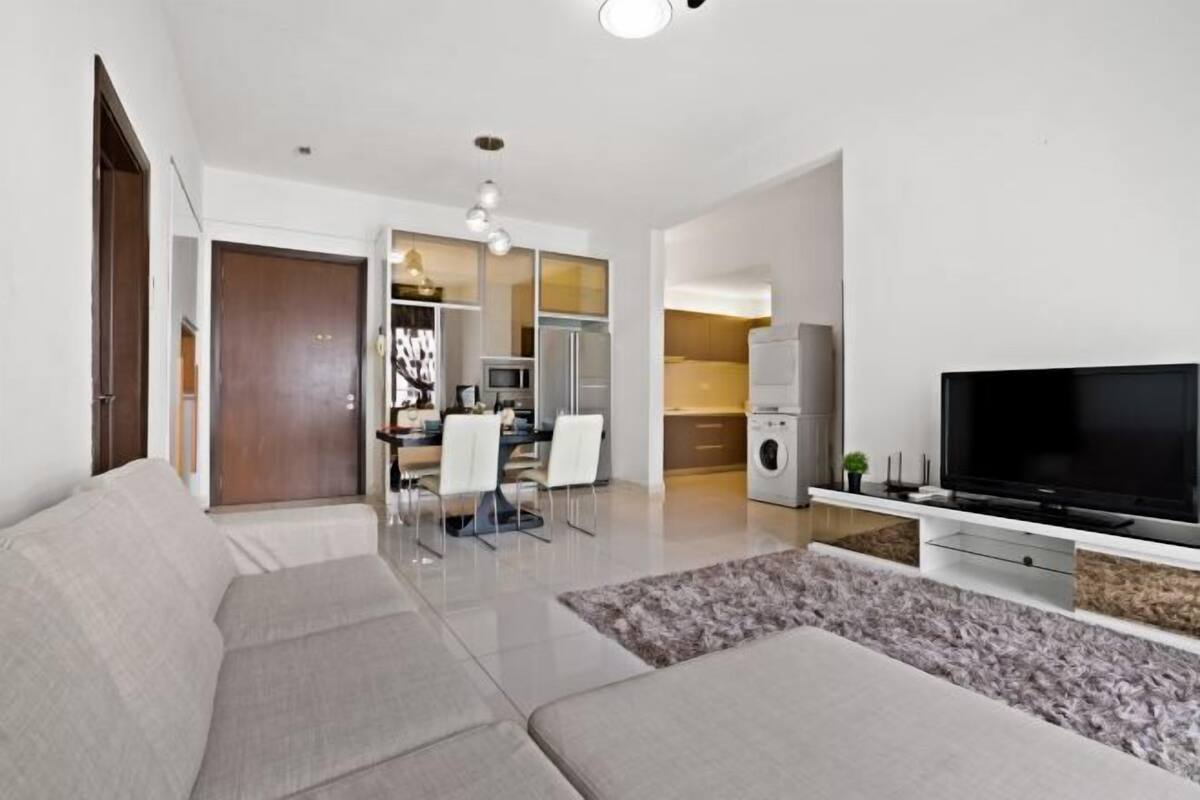 Ein modernes Wohnzimmer mit Sofa, Fernseher und Essbereich mit Stühlen und Tisch.