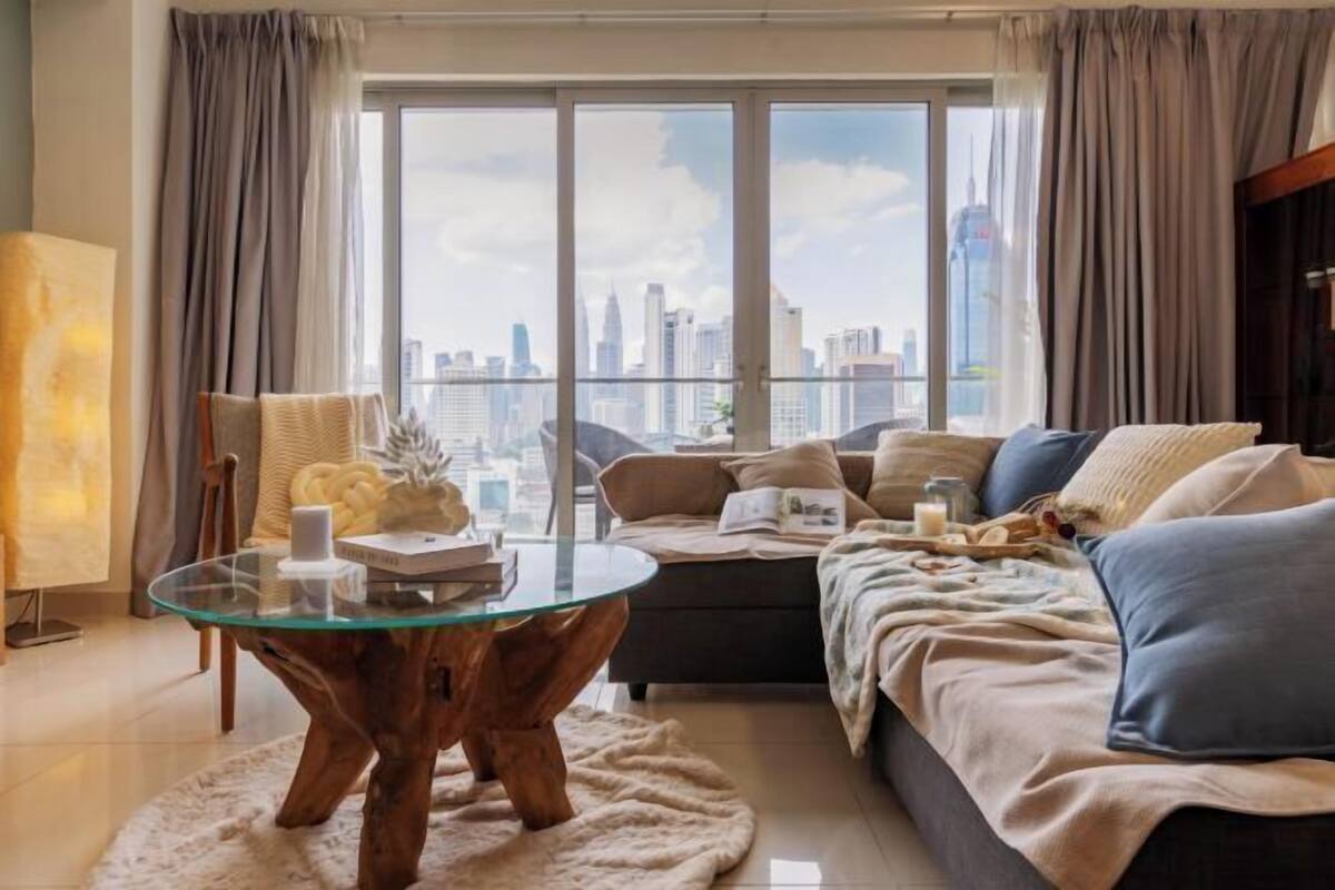 Ein modernes Wohnzimmer mit einem Glastisch, einer Couch und einem großen Fenster mit Blick auf die Stadt.
