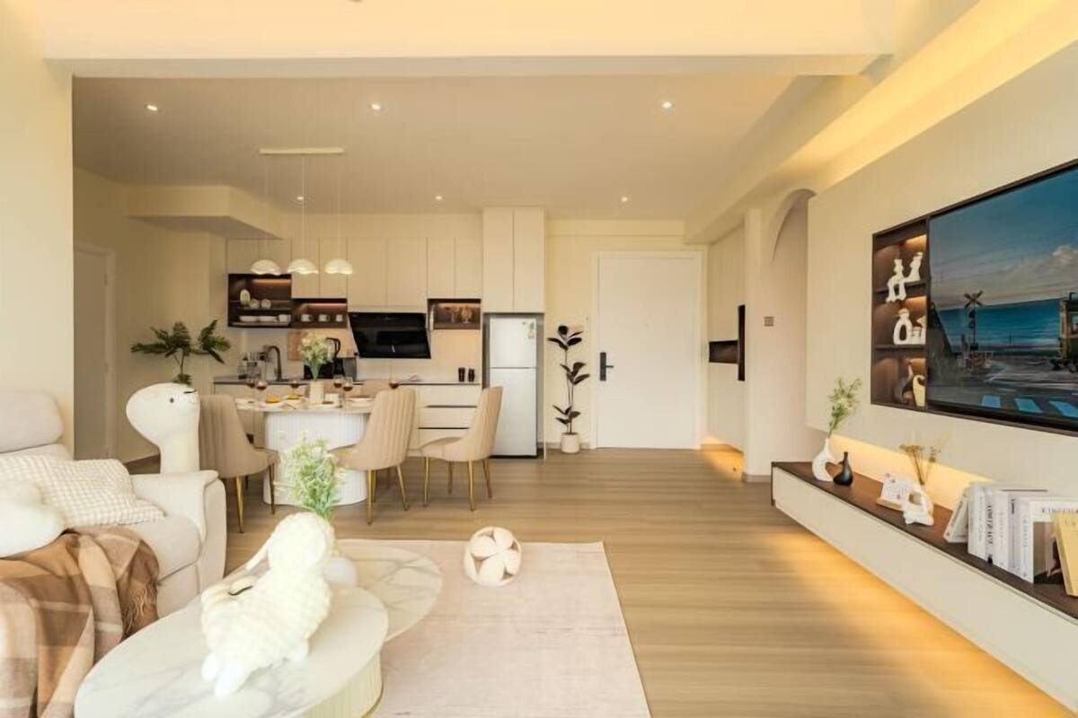 Ein modernes Wohnzimmer mit einer Couch, einem Essbereich und einer Küche im Hintergrund.