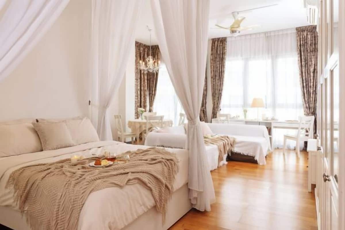 Ein geräumiges Schlafzimmer mit einem großen Bett, einem Schreibtisch und einem Stuhl, alles in einer neutralen Farbgestaltung.