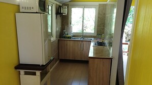 A compact kitchen with a refrigerator, microwave, sink, and wooden cabinets.