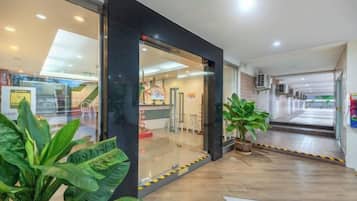 A hotel lobby with a reception desk, potted plants, and a clear view of the entrance.