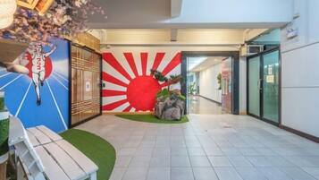 A hotel lobby with a sun mural, a reception desk, and a seating area.