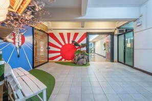 A hotel lobby with a sun mural, a reception desk, and a seating area. - Shibaroom Nakhonratchasima Central Korat (Nakhon Ratchasima)