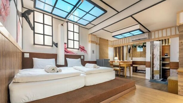 Ein modernes Hotelzimmer mit einem großen Bett, Oberlichtern, einem Holztisch und einem eingebauten Kleiderschrank.