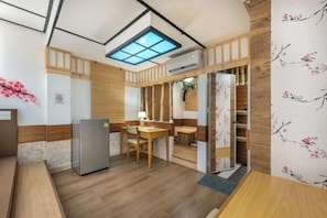 A compact kitchen with a built-in stove, a refrigerator, and a dining area with a table and chairs. - Shibaroom Nakhonratchasima Central Korat (Nakhon Ratchasima)