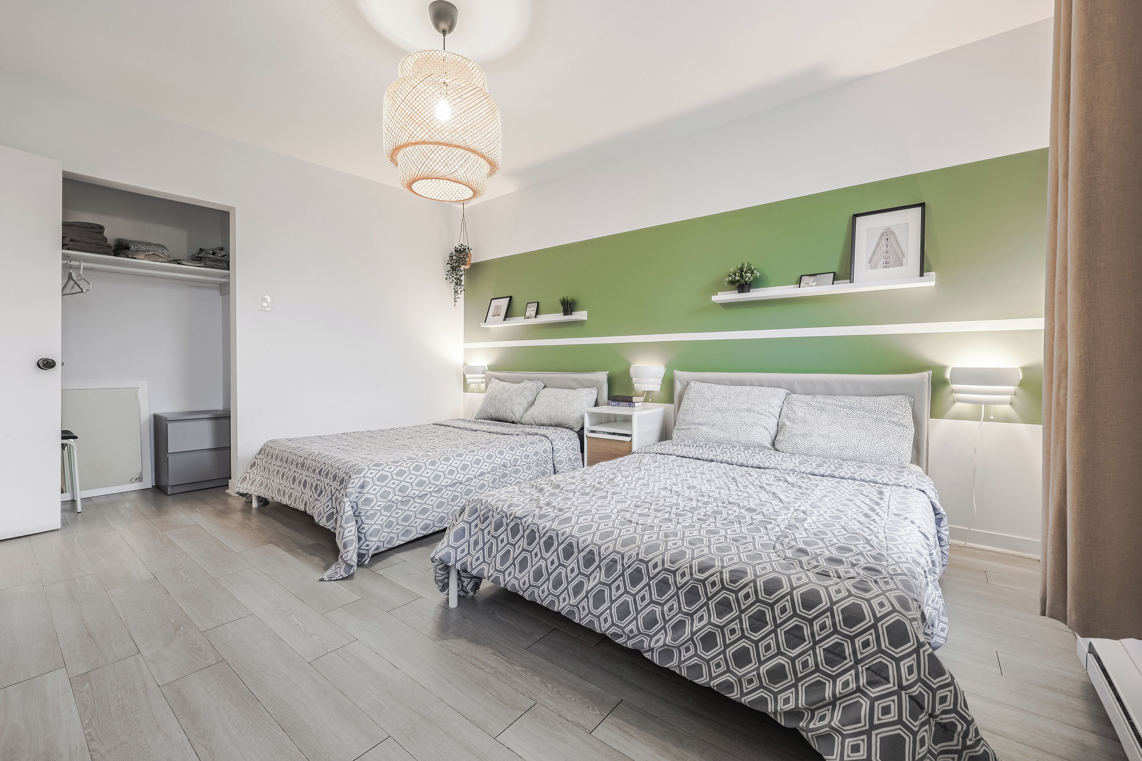 A bedroom with two beds, a wardrobe, and a hanging light fixture.