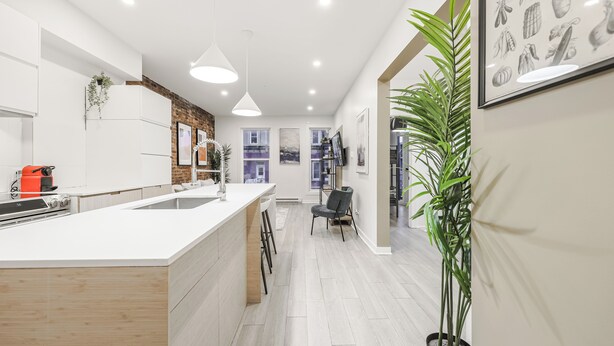 Una cocina moderna con una isla grande, iluminación colgante y vista al comedor.
