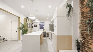Una cocina moderna con una isla central, armarios de madera y una pared de acento de ladrillo.