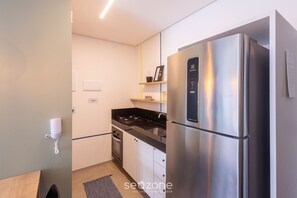 Eine moderne Küche mit einem Edelstahl-Kühlschrank, einem Gasherd und weißen Schränken.
