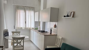 A modern kitchen with white cabinets, a dining table, and a green sofa. - Casetta Martesana - new one-bedroom apartment on the naviglio (Milano)
