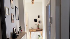 A hallway with a desk, framed pictures, a hanging light fixture, and a telephone. - Casetta Martesana - new one-bedroom apartment on the naviglio (Milano)