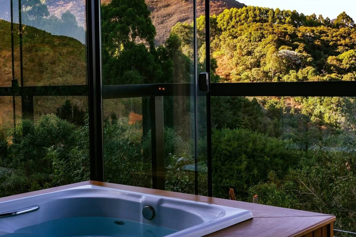 A room with a large window overlooking a forested hillside.