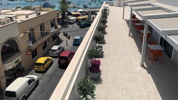 A rooftop terrace with a view of a marina, featuring a row of potted plants and outdoor seating. - Duncan guest house (Marsaxlokk)