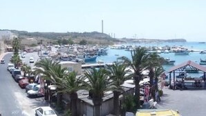A coastal town with a marina filled with boats, a central open square, and buildings along the street. - Duncan guest house (Marsaxlokk)