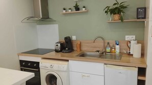 Pieni, mutta toimiva keittiö, jossa on pyykinpesukone, leivänpaahdin, kahvinkeitin ja pesuallas.