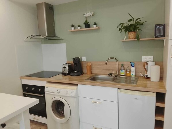 Une cuisine compacte équipée d’un lave-linge, d’un grille-pain, d’une machine à café et d’un évier.