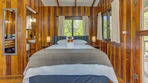A wooden-paneled bedroom with a large bed, a window with curtains, and a mirror. - Kmar Villas (Maya Beach)