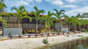 A beachfront resort with wooden cabins, palm trees, and a sandy beach. - Kmar Villas (Maya Beach)