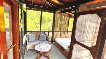Une véranda couverte avec un plafond en bois, un canapé en osier, une petite table et un jacuzzi.