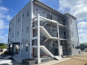 A multi-story building with a central staircase, balconies, and a fire escape.