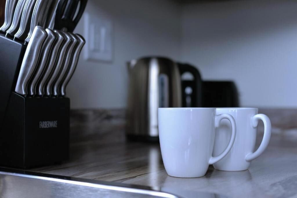 A kitchen counter with a coffee maker and two white mugs.
