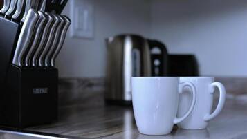A kitchen counter with a coffee maker and two white mugs.