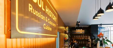 A restaurant interior with a sign indicating 'SOUL HISTORY Russian & Caucasian Cuisine' and a 'FREE WIFI' sign.