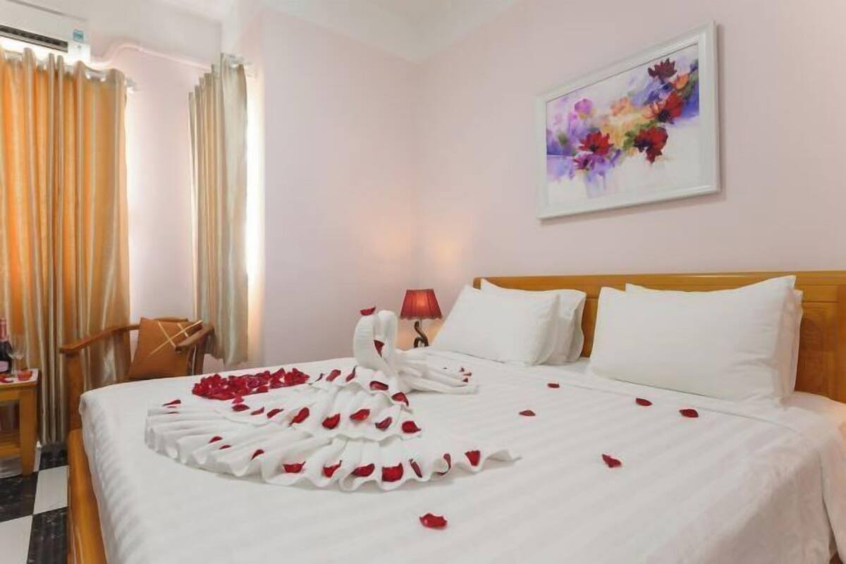 A hotel room with a bed, a nightstand, a lamp, and a painting on the wall.