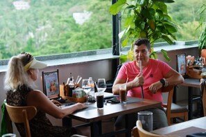Two people seated at a table with a view of greenery outside. - Soul History Hotel Phu Quoc (Phu Quoc Island)