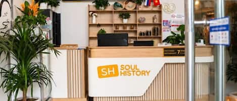 A reception desk with a sign reading 'SOUL HISTORY & LUXY PARK' and a potted plant to the left.