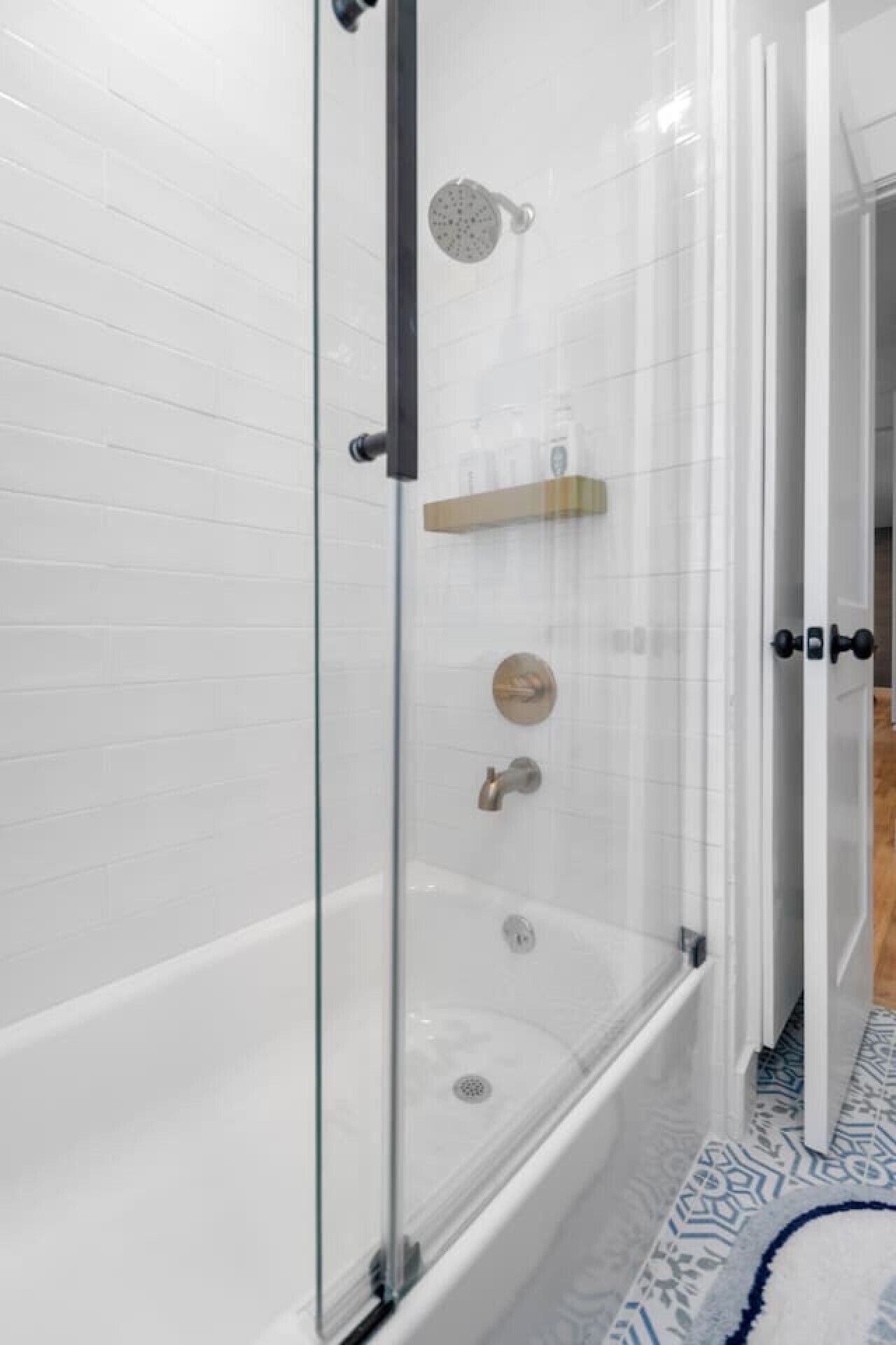 A glass-enclosed walk-in shower with a glass door, a bathtub, and a toilet.