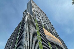 Un edificio alto con líneas verticales y un cartel grande en la fachada.